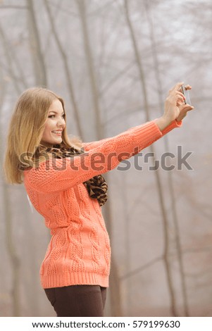 Lovely fashion woman in fall autumn park taking selfie self photo picture. Pretty cute young girl in sweater pullover photographing.