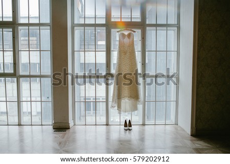 Wedding dress on a hanger on a background window