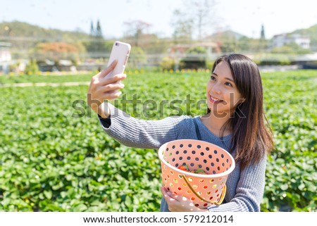Woman taking selfie on cellphone with her strawberry