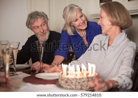 Senior woman and friends with birthday cake