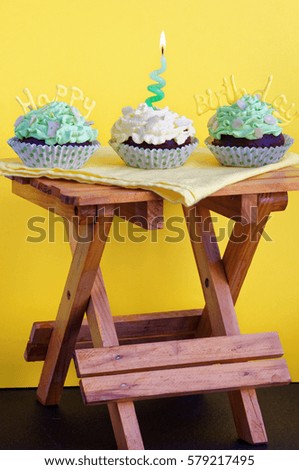 Card with cupcakes for a birthday with decorative inscription "Happy birthday and candle