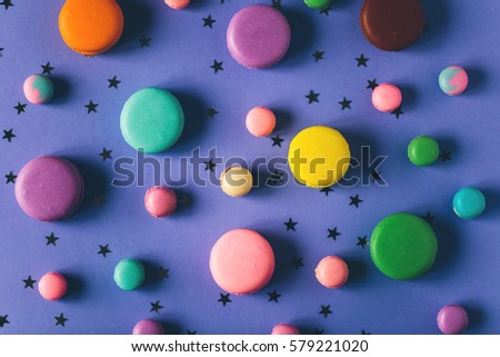 Colorful macaroons on violet background with little stars. Top view, flat lay style.