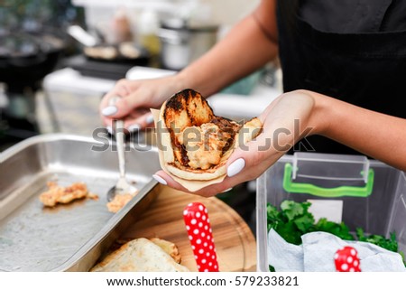 Female street vendor hands put ketchup sauce in taco outdoors. Mexican cuisine snacks, cooking fast food for commercial kitchen.