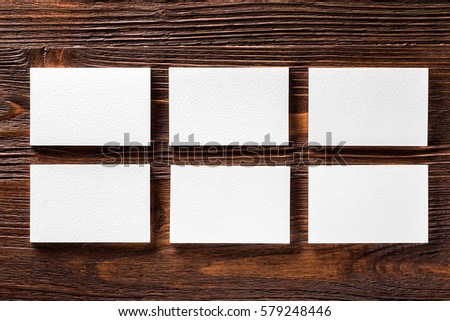 Closeup mockup of six white horizontal business cards at brown wooden table background.