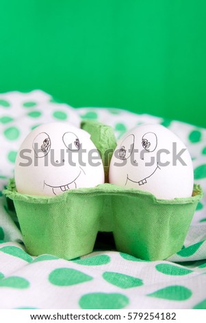 Easter eggs with funny faces in the green box on polka dot tablecloth. Emoji funny egg.