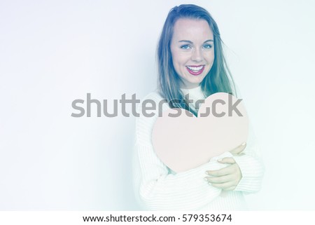 A caucasian woman is smiling holding heart.