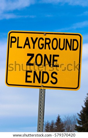 Playground Zone End Sign Against Blue Cloudy Sky and Trees