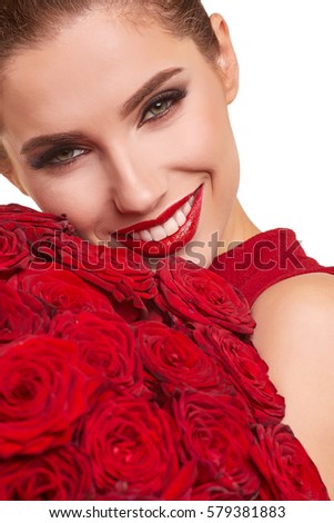 Beautiful surprised woman with red lips posing with flowers in the studio on a valentines day  background.