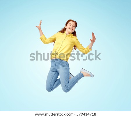 happiness, freedom, motion and people concept - smiling young woman jumping in air over blue background