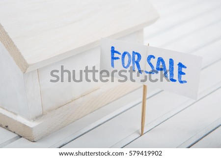 Concept image of model house for sale over wooden background