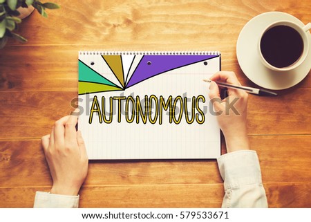 Autonomous text with a person holding a pen on a wooden desk