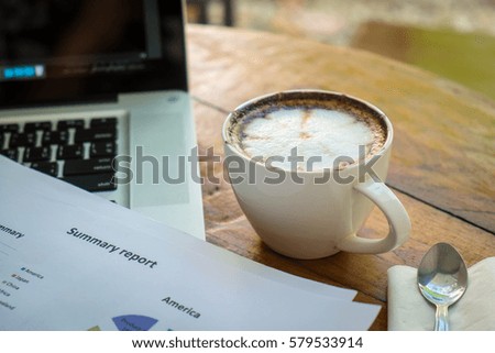 Stack of folders and documents on office desk with coffee and laptop