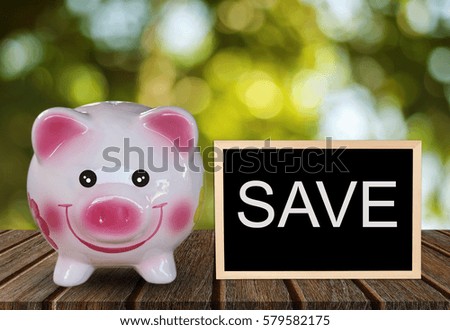 Piggy bank on wooden table and  blackboard with words Save 