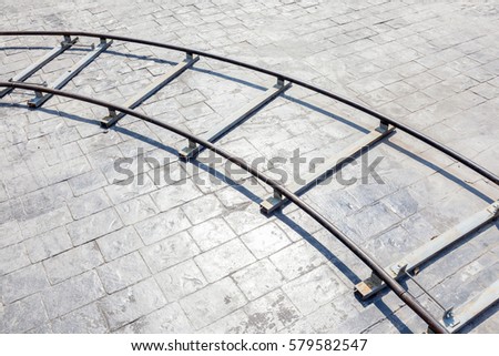The curved part of metal dolly in outdoor location with brick floor background, equipment usage for film industrial.