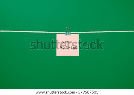 Pink paper note on clothesline with text Good Morning over colorful background