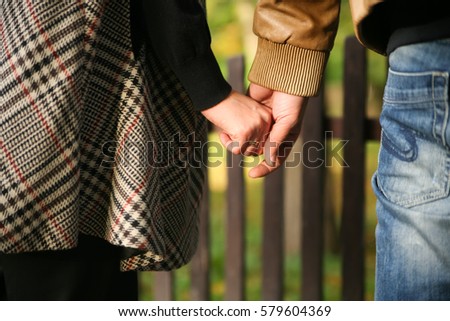 Young married couple holding hands walking in a park