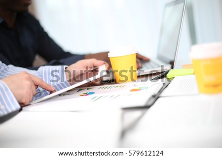 Image of two young businessmen using touchpad at meeting