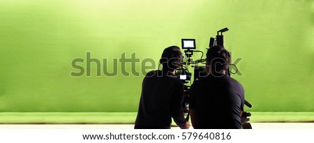 Camera and green screen studio in panorama view and man working or shooting or recording or filming. Royalty-Free Stock Photo #579640816