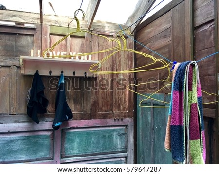 drying underpants and colorful towel with yellow metal hangers in a tropical wooden bathroom
