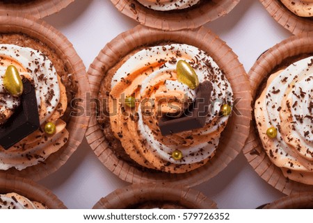 Vanilla cupcakes with orange and white creamcheese and chocolate decor.