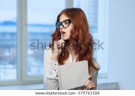 business woman with glasses wearing a white shirt against the backdrop of the city  with a notepad and pen in the hands.