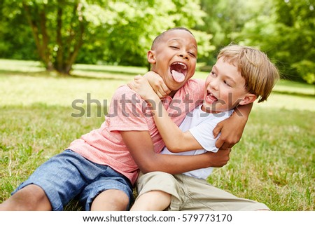 Two boys have fun in the park and wrestle while laughing