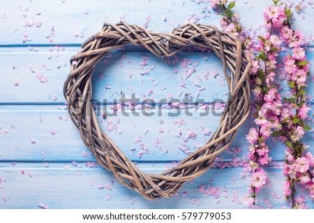 Decorative  heart and pink sakura flowers  on blue wooden background. Selective focus. Flat lay.  St. Valentine day background.
