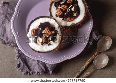 Fruit salad with coconut, banana, yogurka drizzled with hot dark chocolate. Dark background