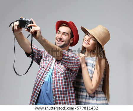 Couple of travelers taking picture of themselves on color background