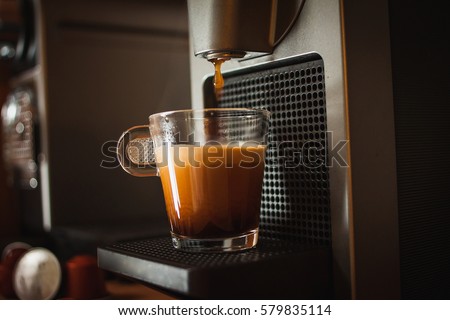 A cup of coffee on the coffee machine. One drop of coffee pouring into cup Royalty-Free Stock Photo #579835114