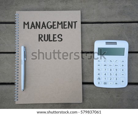 Business concept. Calculator, pen and notebook with word on wooden table. MANAGEMENT RULES