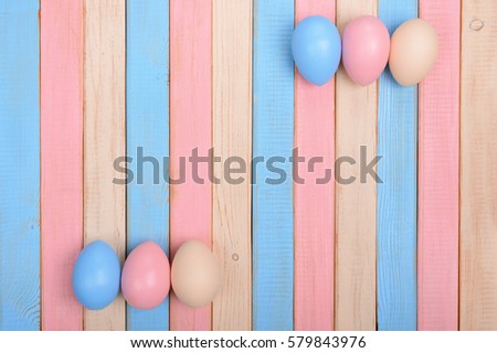 Colorful easter eggs on varicolored wooden background/ top view