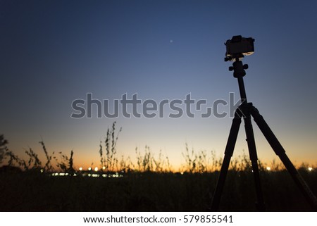 Camera tripod with sunset and blue sky for background concept design