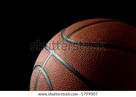 Brand new basketball on black background lit from the side with space for copy above and to the left