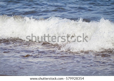 Cold blue sea water surf over seashore. Chilly sea wave splashes over coast. Empty beach of tropical island. Idyllic seascape for summer vacation or travel background. Exotic seaside banner template