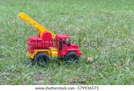 A toy fire truck laying on the grass.