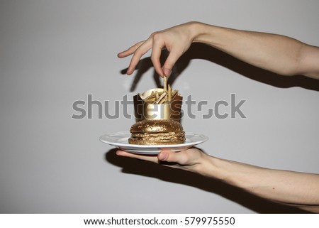 Conceptual avant-guard picture of fast food burger and chips painted with a gold.