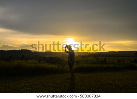 Silhouette man during to take off his hat in the evening before sunset