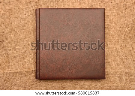 brown leather photo album cover on jute background. Keeping memories alive throughout the years concept Royalty-Free Stock Photo #580015837