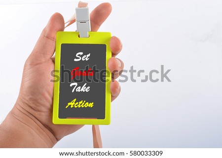 Hand holding name tag with text "Set Goals Take Action"