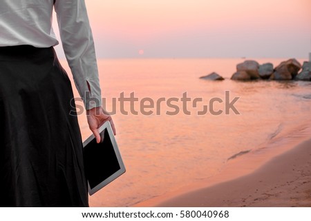 young business woman relaxing working Using tablet and Toe Foot touches the sea on the beach At the time of sunset . happy at work Concept .