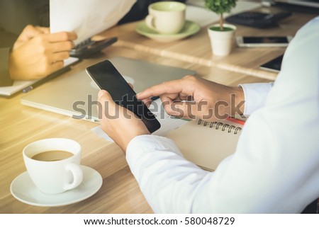 Businessman using a smart phone to see information. While attending a meeting of business.