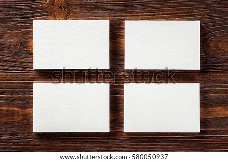 Closeup mockup of four blank vertical business cards at brown wooden table background.