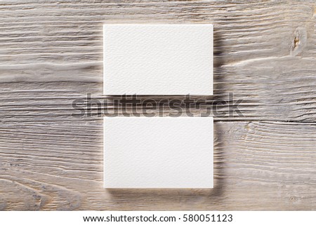 Closeup mockup of two blank horizontal business cards at light natural wooden background.