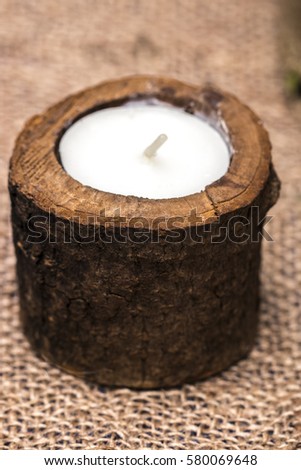 Candle in a wooden candlestick on a romantic background.