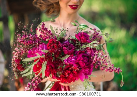 The bride holds a chic wedding bouquet of roses and peony. Royalty-Free Stock Photo #580100731