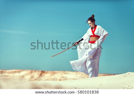 Samurai Girl with a sword in the desert. Royalty-Free Stock Photo #580101838