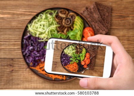 Hands taking photo Buddha bowl of mixed vegetable with smartphone.