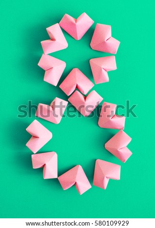 Happy International Women’s Day celebrate on March 8 CARD.  rose-color paper hearts shape figure eight on a green background
