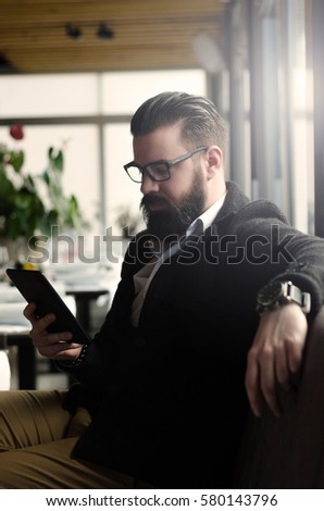 hipster man or a man with a beard using tablet in the coffee shop